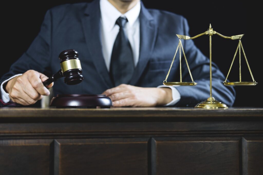 A man in suit and tie sitting at a table with a gavel.