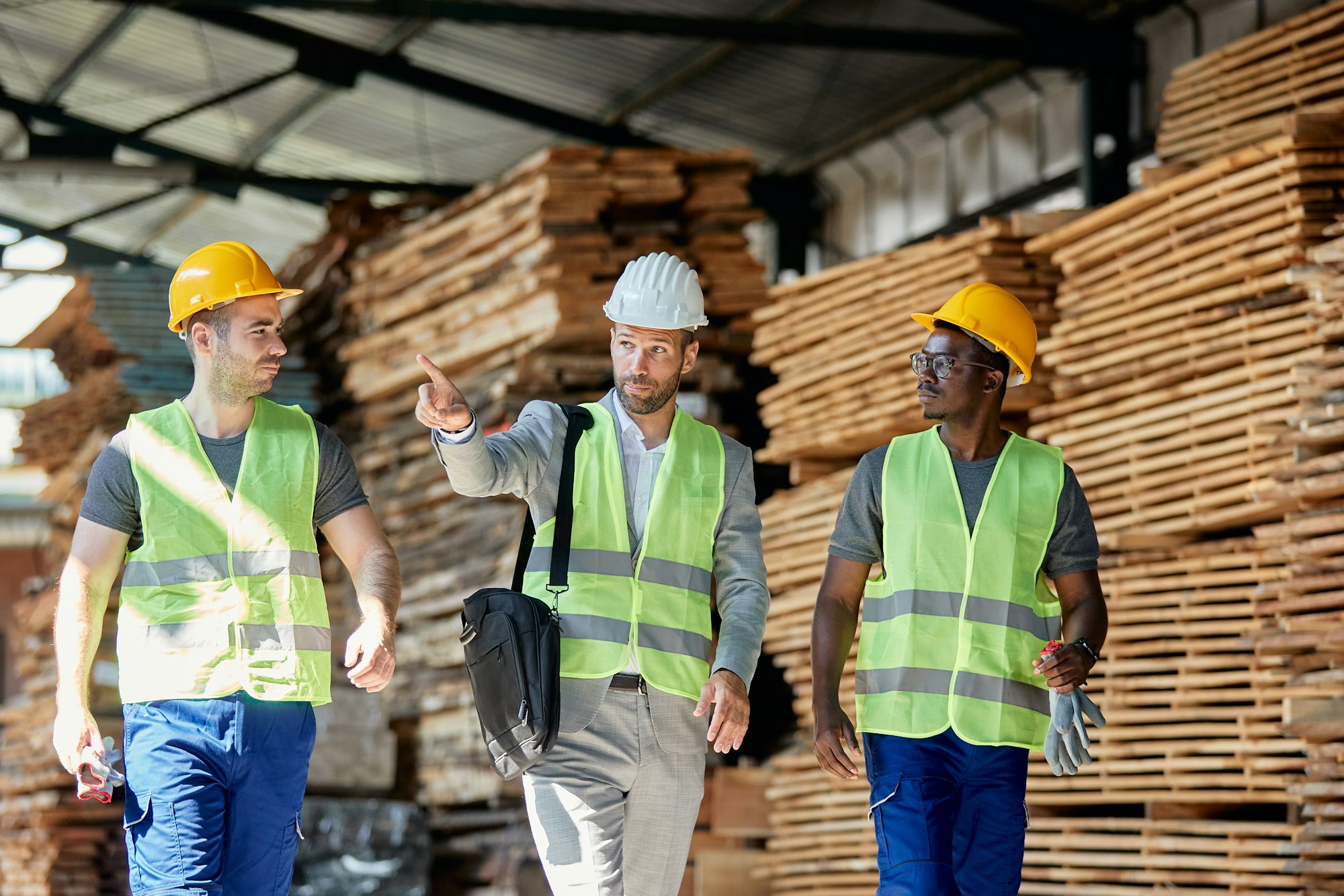 Wood warehouse owner communicating with employees while walking through storage compartment.